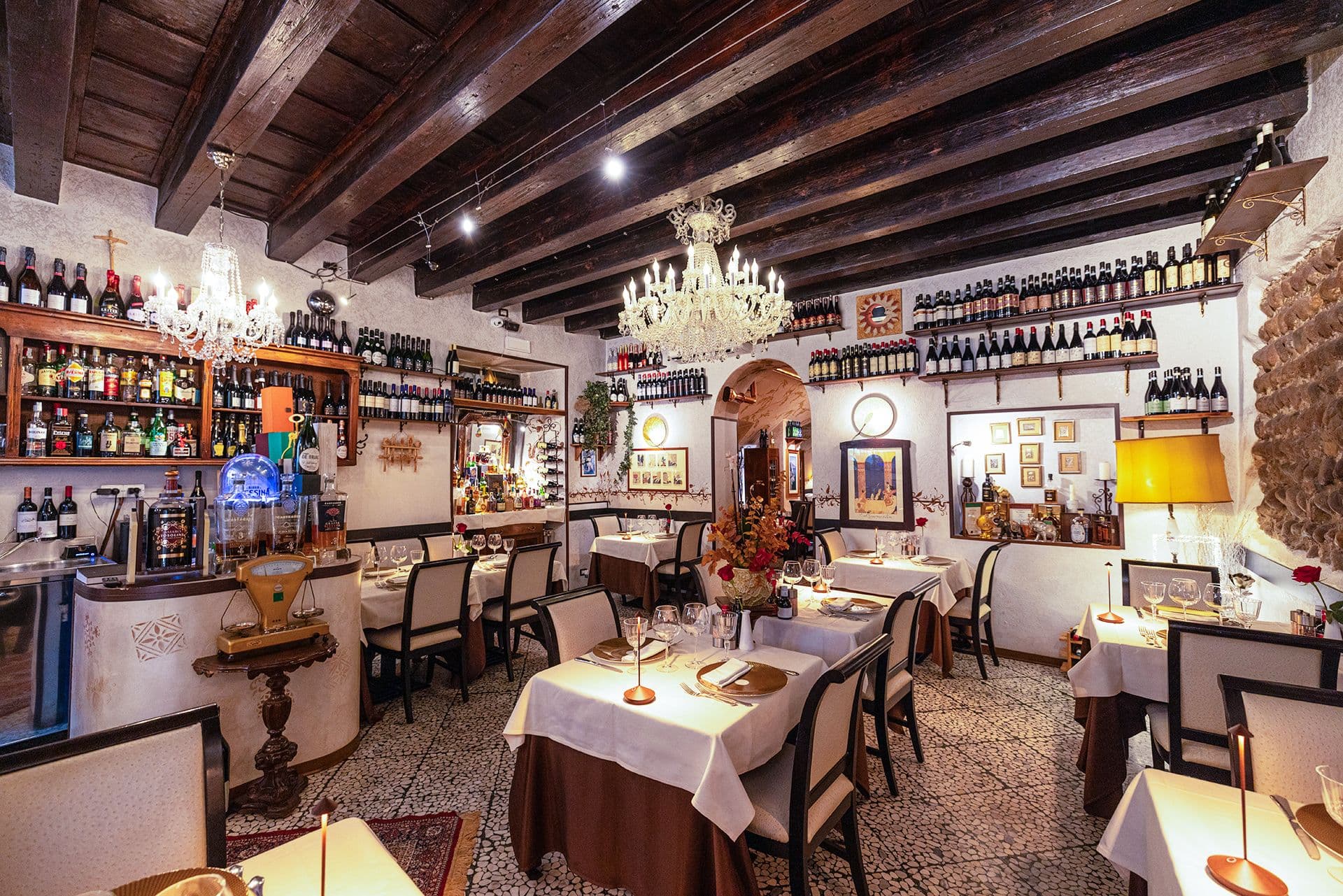 Sala principale de La Vecia Mescola: travi a vista, lampadari e muro in pietra